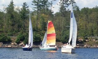 Three Mazinaw boats sail in close company with a backdrop of broken trees. Photo by Lynda Dunal.